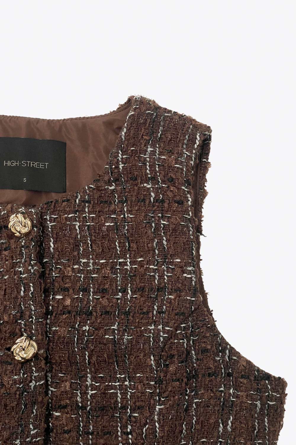 Chaleco de bouclé fit ajustado, cuello redondo, vivos decorativos frontales, cierre con hilera de botones en contraste y abertura frontal en bajo.