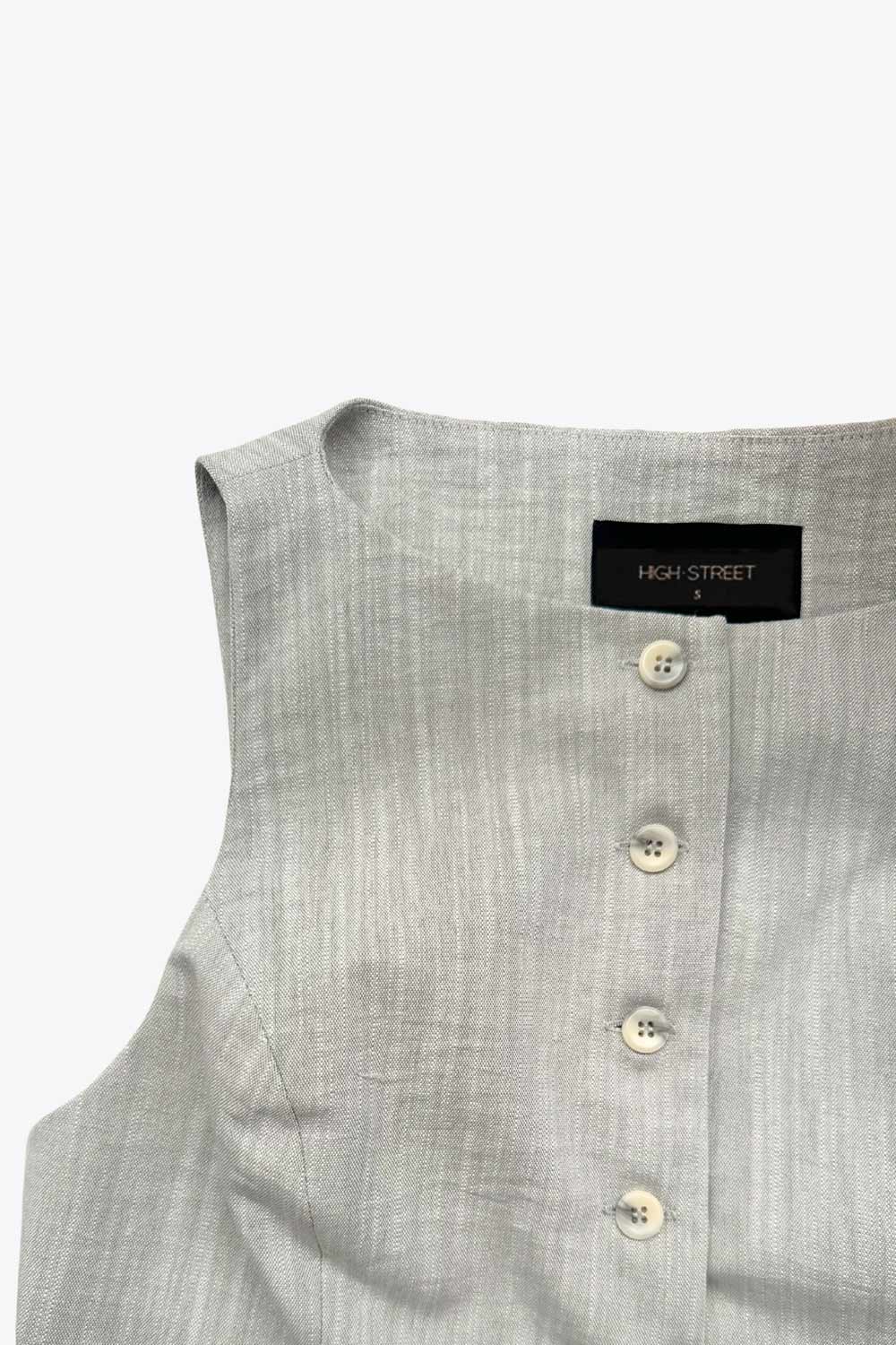 Chaleco corto de fit recto, cuello barco, vivos decorativos delanteros, bajo v frontal y cierre con hilera de botones.
