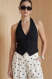 Chaleco corto cuello halter, fit ajustado, escote v, cierre frontal con hilera oculta de botones, vivos decorativos frontales y bajo v frontal. Escote en espalda y detalle de trabilla ajustable posterior.