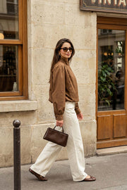 Chamarra corta de fit abullonado, cuello alto, manga larga abullonada con puño abotonado y cierre frontal con cremallera oculta. Detalle de plisados decorativos frontales y trabillas con botón en cuello.