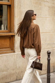 Chamarra corta de fit abullonado, cuello alto, manga larga abullonada con puño abotonado y cierre frontal con cremallera oculta. Detalle de plisados decorativos frontales y trabillas con botón en cuello.