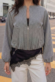 Chamarra bomber de manga larga abullonada con rib en puños y hombro caído, cuello redondo, bolsillos delanteros con vivos, bajo en con rib elástico y cierre frontal con cremallera visible en contraste.