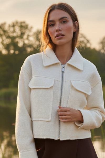 Chamarra corta de borreguillo, fit recto, manga larga con puño abotonado, cuello solapa, bolsillos frontales de parche con cartera y cierre frontal con cremallera visible en contraste.