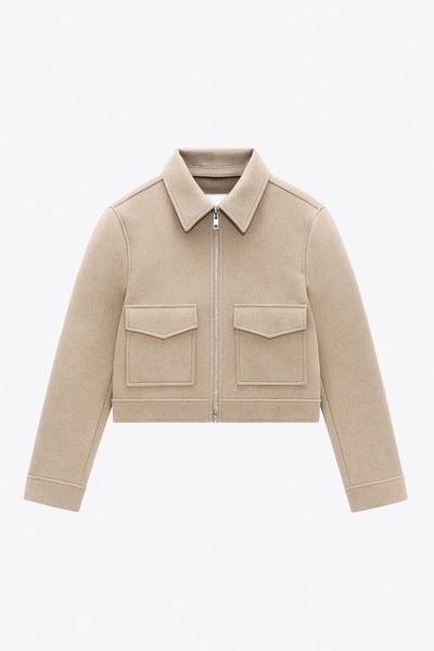 Chamarra corta de fit recto, manga larga con puño abotonado, cuello camisero, bolsillos delanteros de parche con cartera y cierre frontal con cremallera visible en contraste.