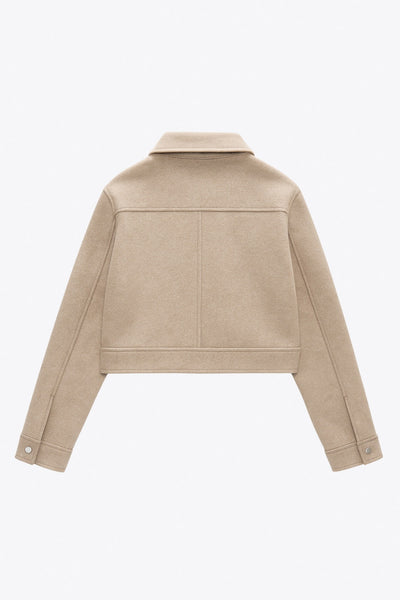 Chamarra corta de fit recto, manga larga con puño abotonado, cuello camisero, bolsillos delanteros de parche con cartera y cierre frontal con cremallera visible en contraste.