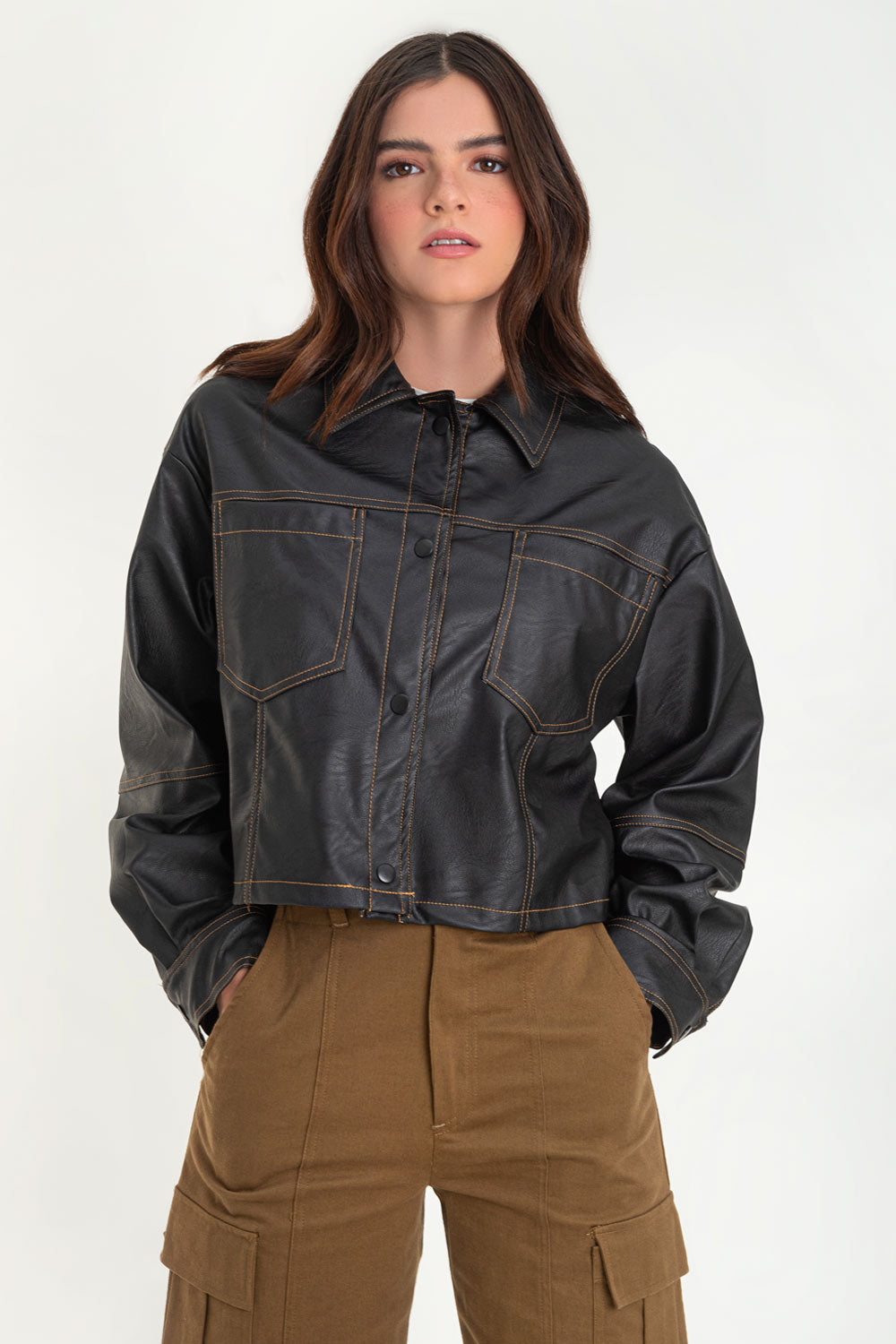 Chamarra corta de efecto piel, fit recto, cuello camisero, manga larga con puño abotonado, bolsillos delanteros de parche y cierre frontal con hilera de botones de presion. Detalle de costuras decorativas en contraste.