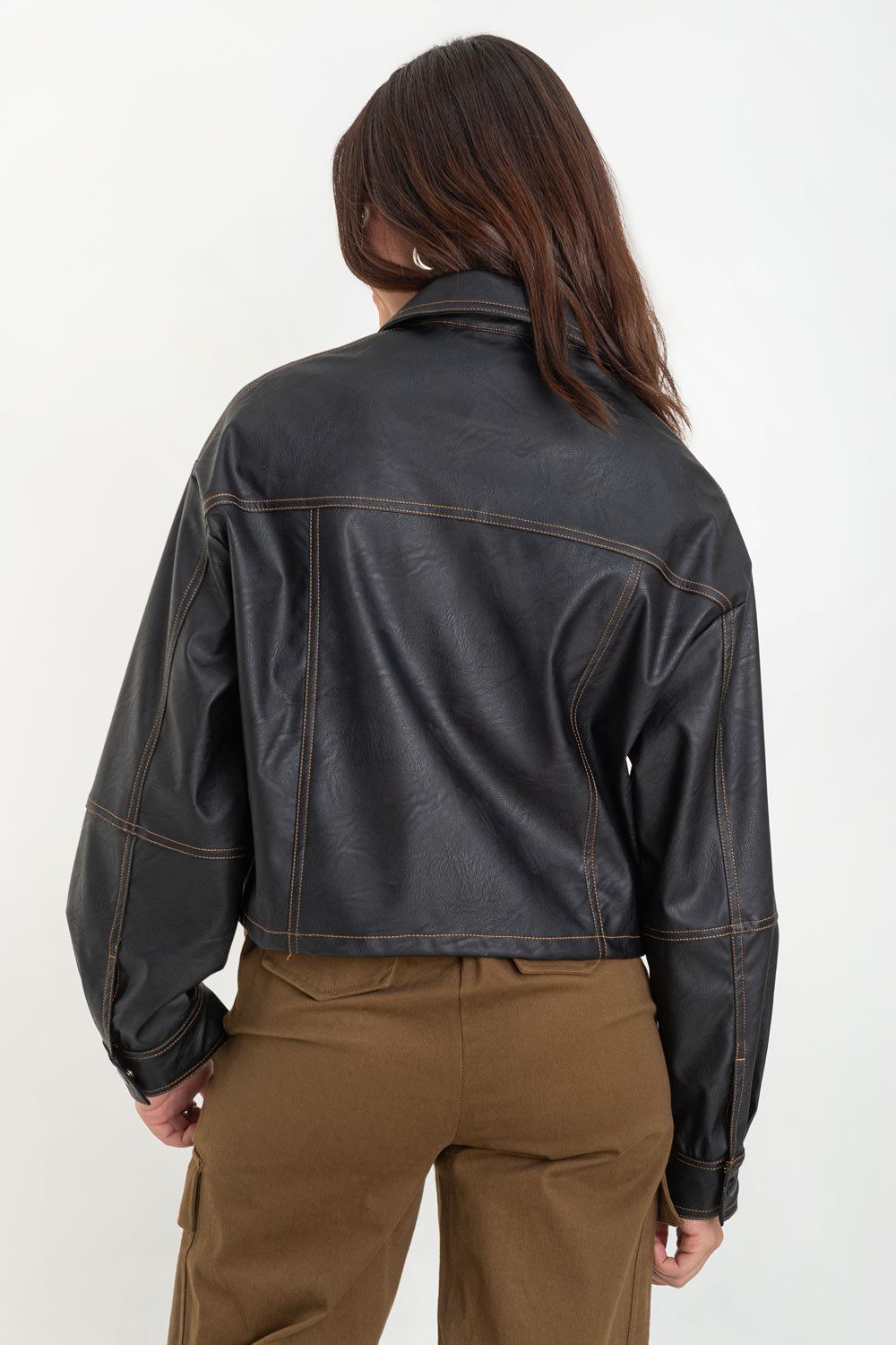 Chamarra corta de efecto piel, fit recto, cuello camisero, manga larga con puño abotonado, bolsillos delanteros de parche y cierre frontal con hilera de botones de presion. Detalle de costuras decorativas en contraste.