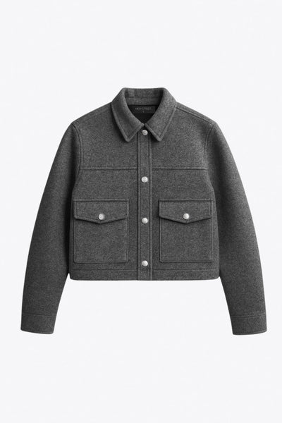 Chamarra corta de fit recto, cuello camisero, manga larga con puño abotonado, cortes decorativos frontales, bolsillos delanteros con cartera y botón. Cierre frontal con hilera de botones en contraste.