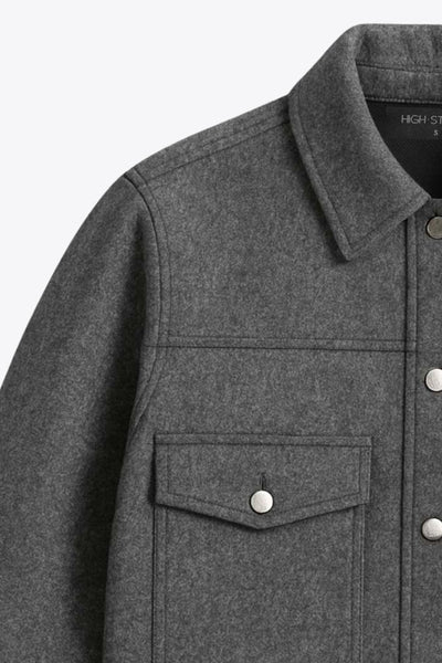 Chamarra corta de fit recto, cuello camisero, manga larga con puño abotonado, cortes decorativos frontales, bolsillos delanteros con cartera y botón. Cierre frontal con hilera de botones en contraste.