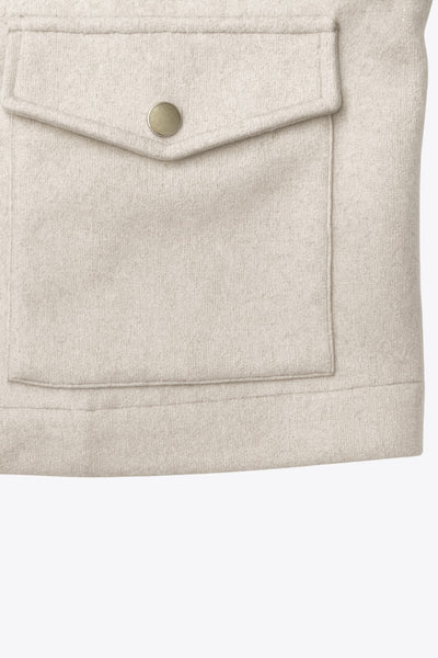 Chamarra corta de fit recto, cuello camisero, manga larga con puño abotonado, cortes decorativos frontales, bolsillos delanteros con cartera y botón. Cierre frontal con hilera de botones en contraste.