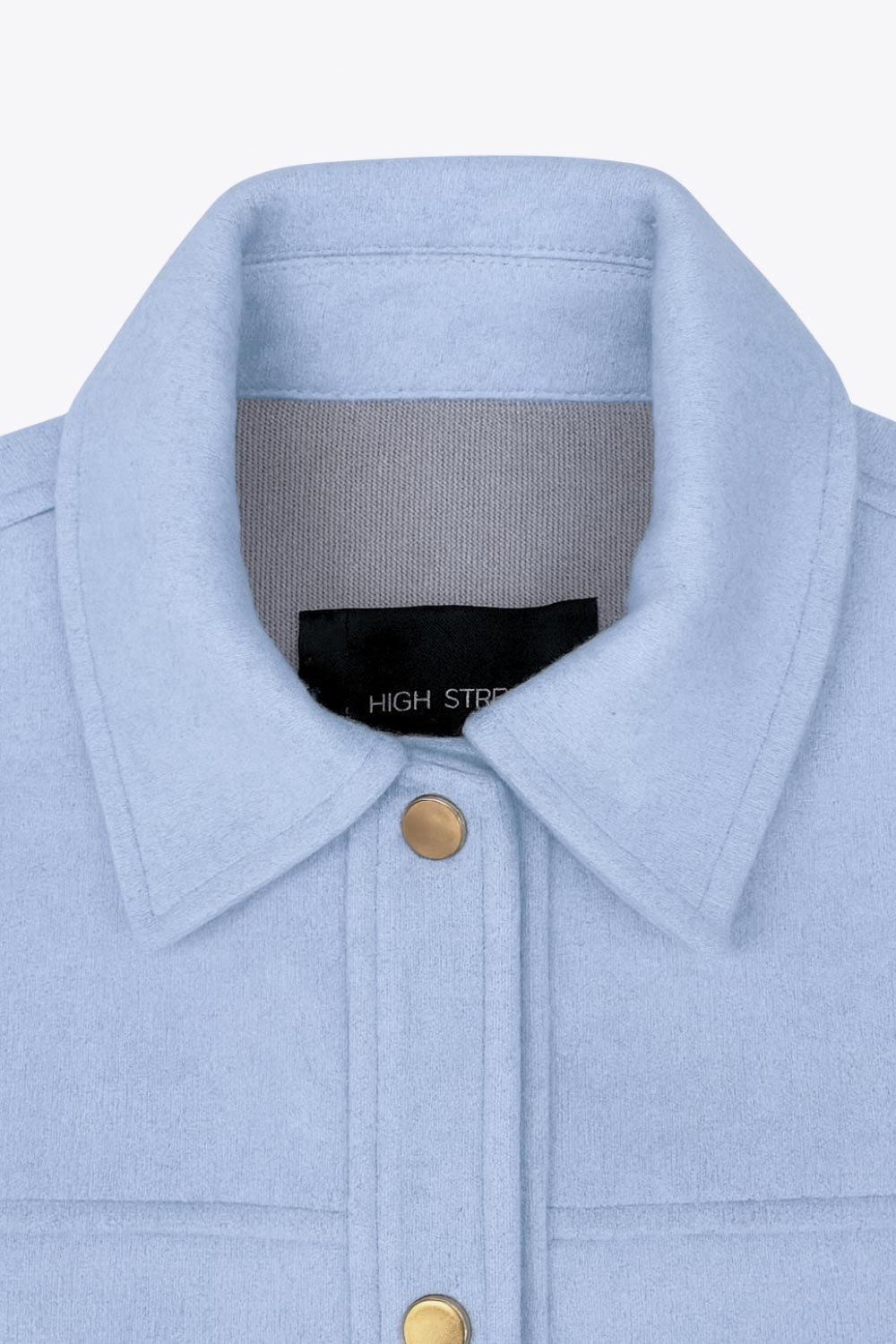 Chamarra corta de fit recto, cuello camisero, manga larga con puño abotonado, cortes decorativos frontales, bolsillos delanteros con cartera y botón. Cierre frontal con hilera de botones en contraste.