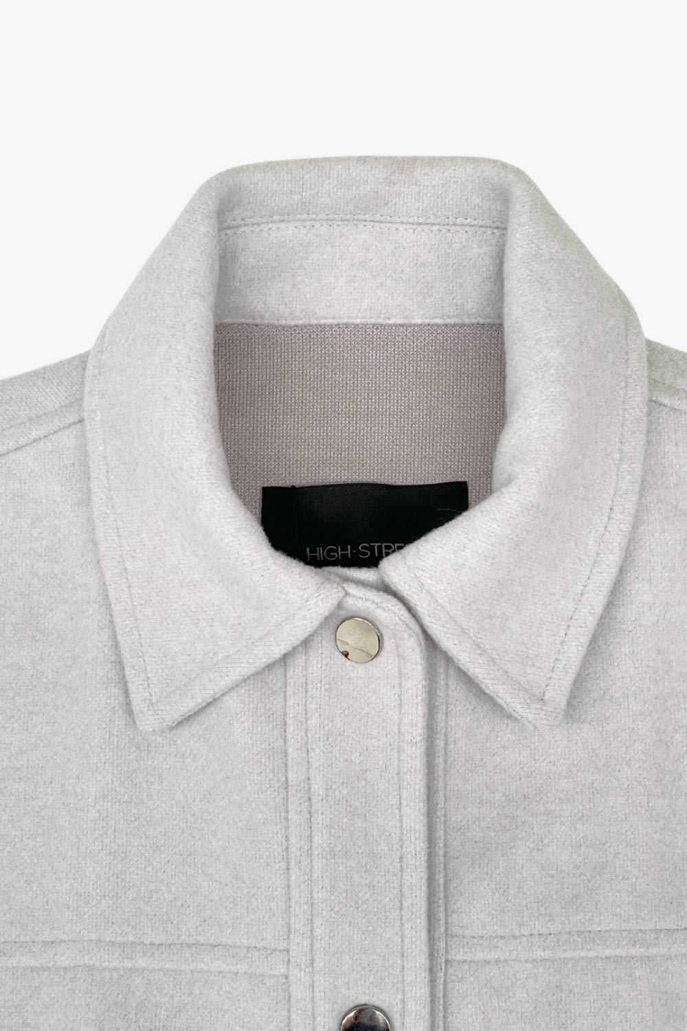 Chamarra corta de fit recto, cuello camisero, manga larga con puño abotonado, cortes decorativos frontales, bolsillos delanteros con cartera y botón. Cierre frontal con hilera de botones en contraste.