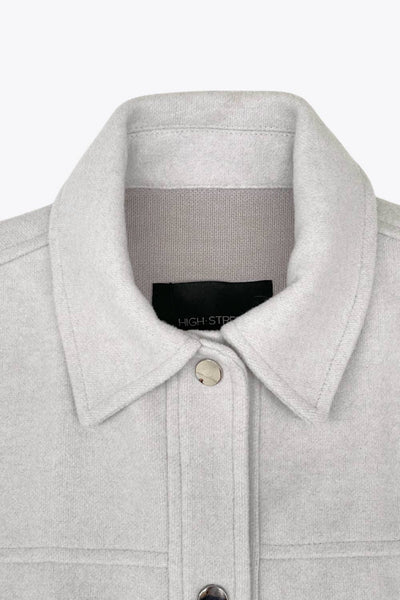 Chamarra corta de fit recto, cuello camisero, manga larga con puño abotonado, cortes decorativos frontales, bolsillos delanteros con cartera y botón. Cierre frontal con hilera de botones en contraste.