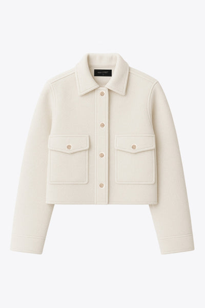 Chamarra corta de fit recto, cuello camisero, manga larga con puño abotonado, bolsillos delanteros con cartera y botón. Cierre frontal con hilera de botones en contraste.