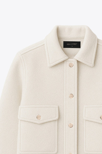 Chamarra corta de fit recto, cuello camisero, manga larga con puño abotonado, bolsillos delanteros con cartera y botón. Cierre frontal con hilera de botones en contraste.