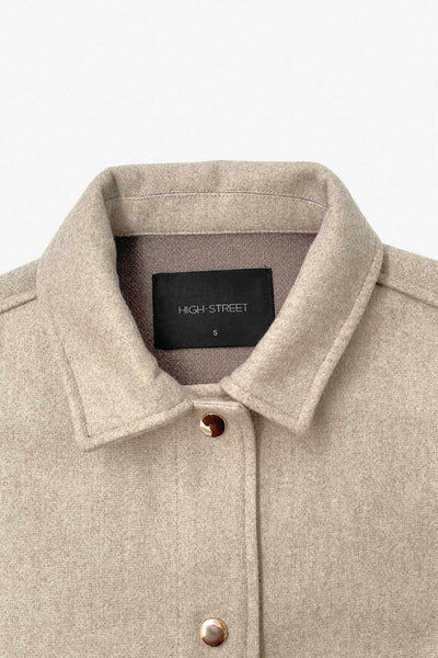 Chamarra corta de fit recto, cuello camisero, manga larga con puño abotonado, bolsillos delanteros con cartera y botón. Cierre frontal con hilera de botones en contraste.