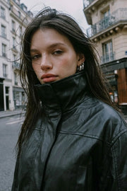 Chamarra de efecto piel, fit oversized, manga larga con puño abotonado, cuello alto, bolsillos delanteros con vivos, cortes decorativos y elástico en bajo. Cierre frontal con cremallera oculta.