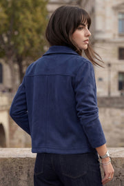 Chamarra corta de gamuza, fit recto, manga larga, cuello camisero, bolsillos delanteros de parche y cierre frontal con hilera de botones en contraste.