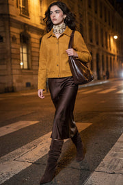 Chamarra corta de gamuza, fit recto, manga larga, cuello camisero, bolsillos delanteros de parche y cierre frontal con hilera de botones en contraste.