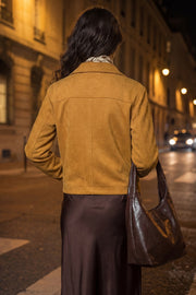 Chamarra corta de gamuza, fit recto, manga larga, cuello camisero, bolsillos delanteros de parche y cierre frontal con hilera de botones en contraste.