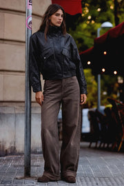 Chamarra de efecto piel, fit oversized, manga larga con puño abotonado, cuello alto, bolsillos delanteros con vivos y carteras, cortes decorativos y pretina elástica. Cierre frontal con cremallera oculta.