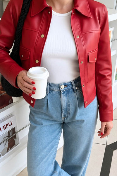 Chamarra corta de efecto piel, fit recto, cuello camisero, manga larga con puño abotonado, bolsillos delanteros de parche con botones y cierre frontal con botones de presión en contraste.