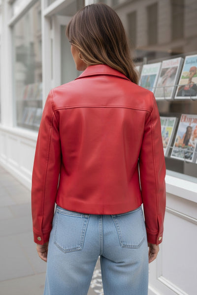 Chamarra corta de efecto piel, fit recto, cuello camisero, manga larga con puño abotonado, bolsillos delanteros de parche con botones y cierre frontal con botones de presión en contraste.