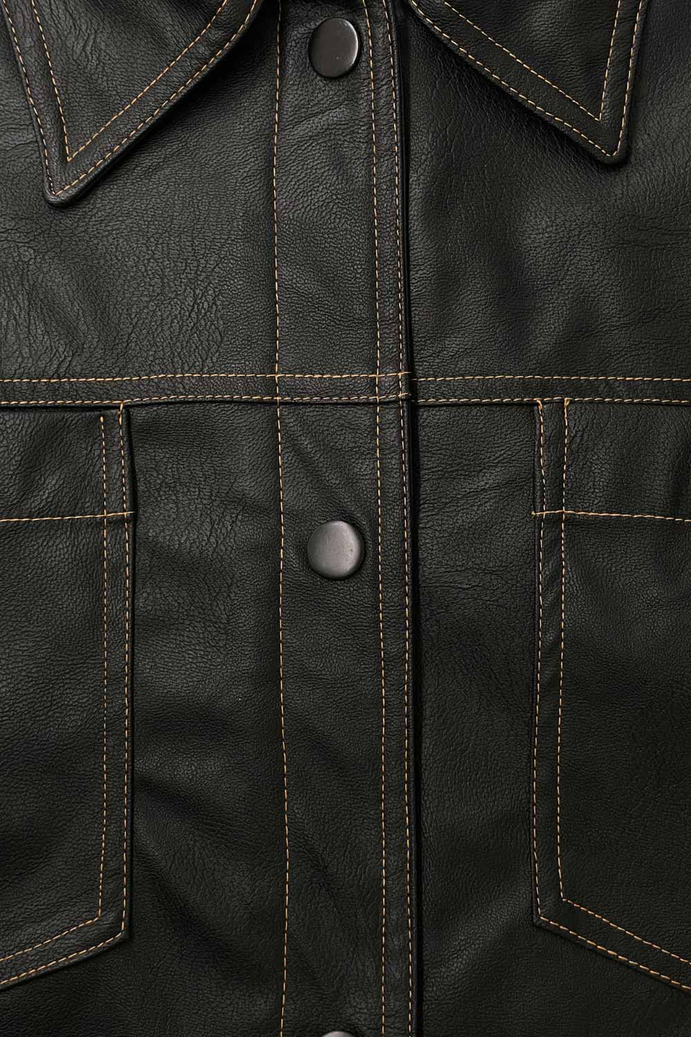 Chamarra corta de efecto piel, fit recto, cuello camisero, manga larga con puño abotonado, bolsillos delanteros de parche y cierre frontal con hilera de botones de presión. Detalle de costuras decorativas en contraste.