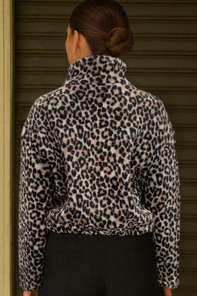 Chamarra de efecto borreguillo, estampado leopardo, manga larga, cuello alto y cierre frontal con cremallera visible en contraste.