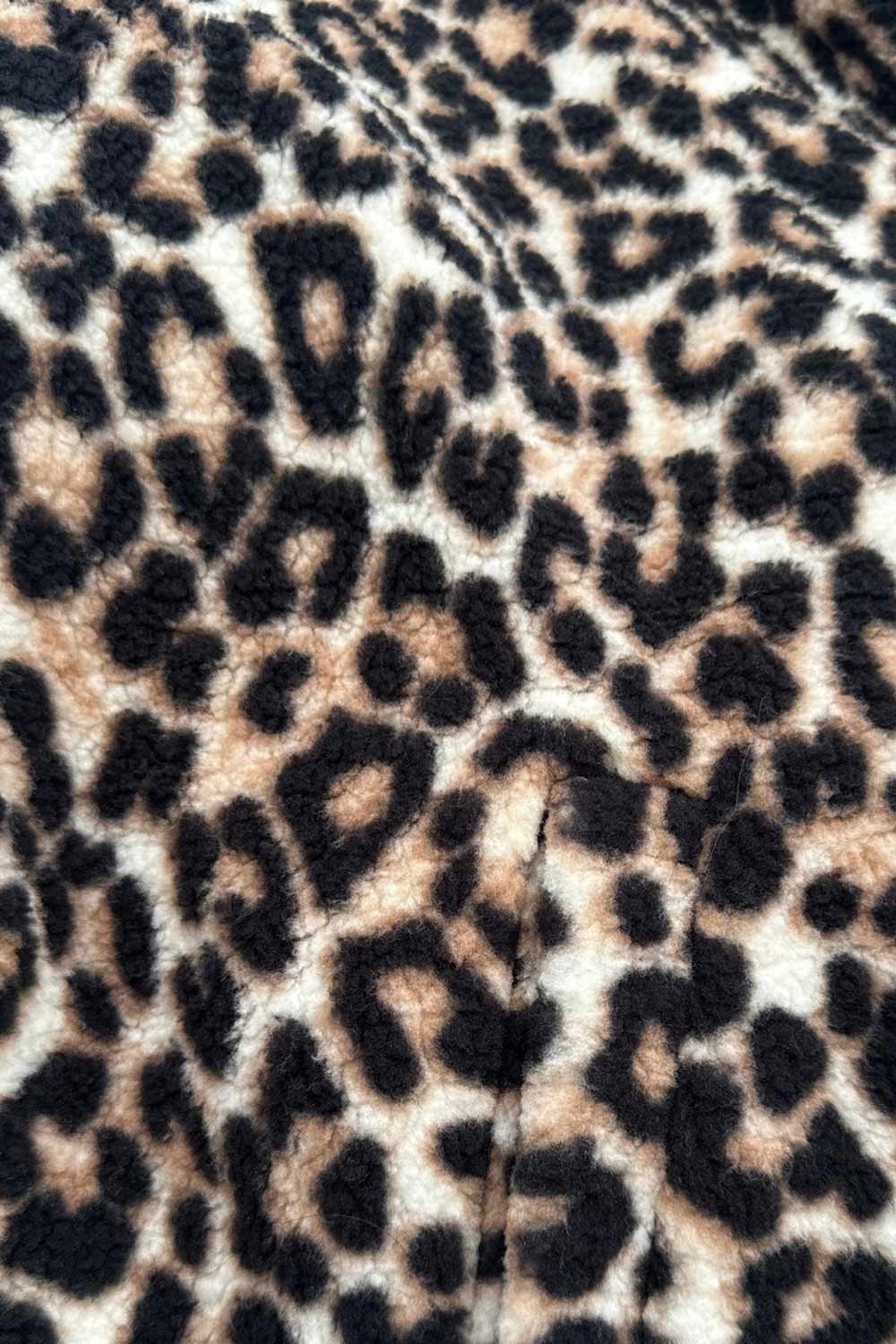 Chamarra de efecto borreguillo, estampado leopardo, manga larga, cuello alto y cierre frontal con cremallera visible en contraste.