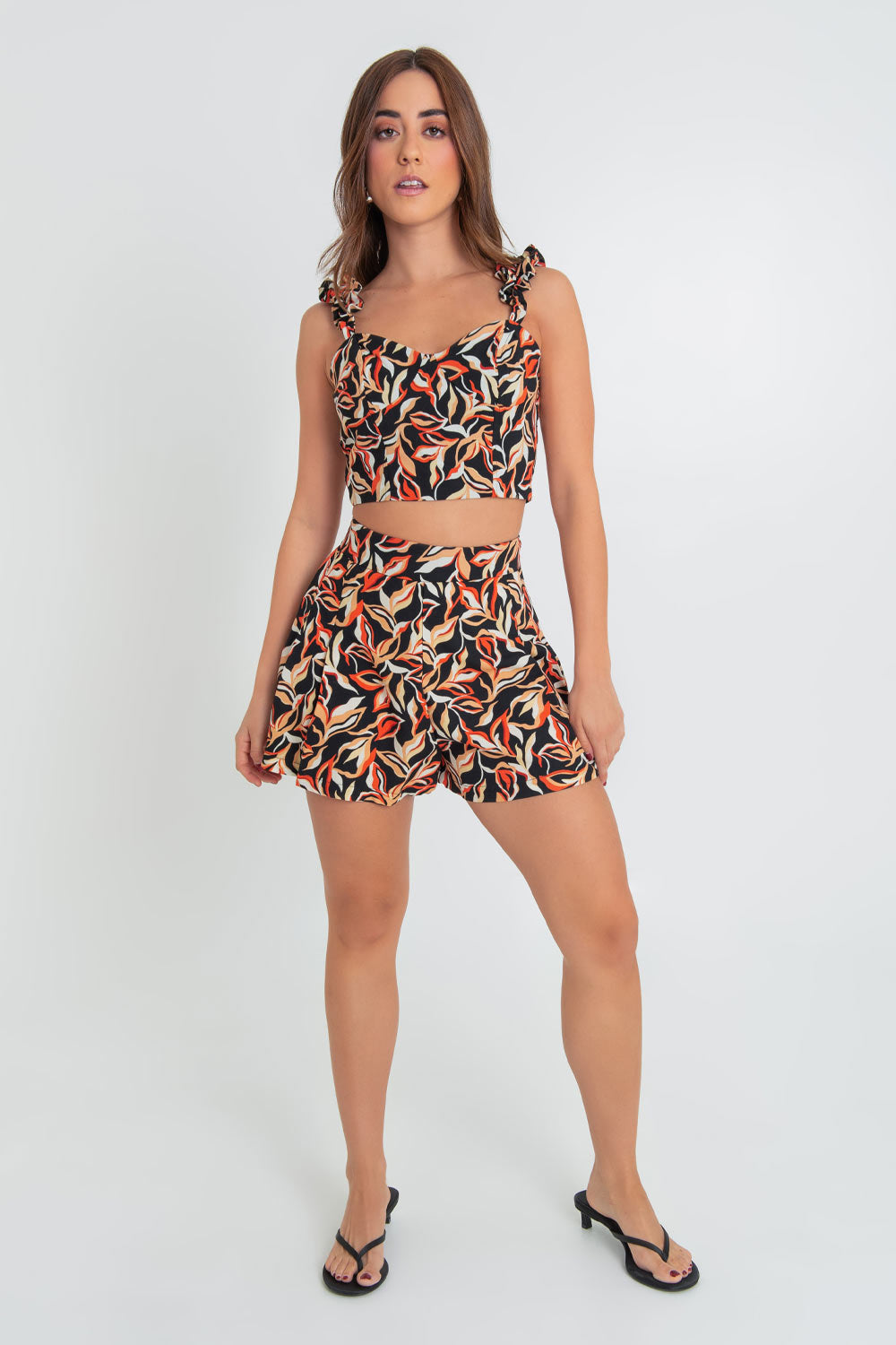 Crop top de estampado abstracto, fit ajustado, escote corazón con cortes decorativos, costuras frontales y tirantes fruncidos con olanes. Cierre posterior con cremallera visible en contraste.