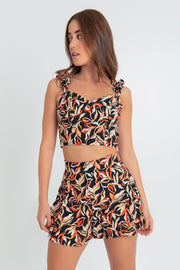 Crop top de estampado abstracto, fit ajustado, escote corazón con cortes decorativos, costuras frontales y tirantes fruncidos con olanes. Cierre posterior con cremallera visible en contraste.