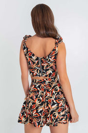 Crop top de estampado abstracto, fit ajustado, escote corazón con cortes decorativos, costuras frontales y tirantes fruncidos con olanes. Cierre posterior con cremallera visible en contraste.