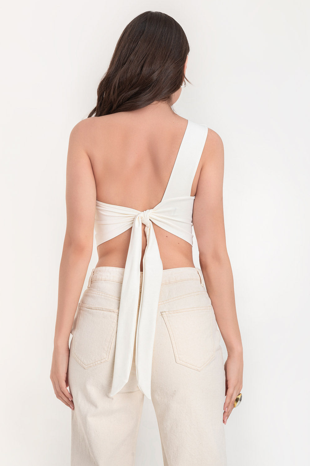 Crop top asimétrico de un hombro, sin mangas, fit ajustado, escote diagonal, escote en espalda, bajo frontal asimétrico y cierre posterior con nudo amarrable.