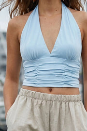 Crop top de fit ajustado, cuello halter con nudo amarrable posterior, escote v con cortes frontales, plisados decorativos y cierre posterior con nudo amarrable.