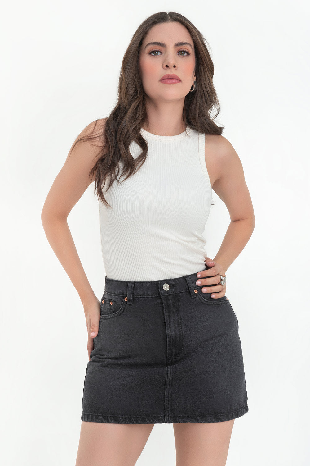 Falda corta básica de denim, fit ajustado, cintura alta con pretina y trabillas, bolsillos delanteros y traseros de parche. Cierre frontal con botón y cremallera oculta.