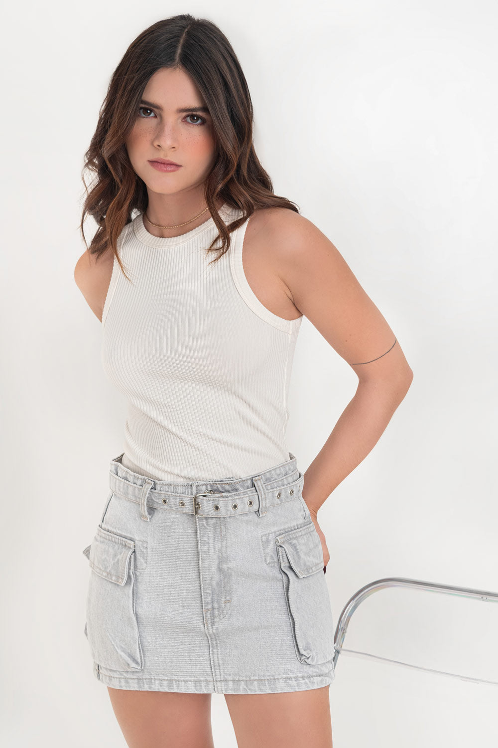 Falda corta cargo de denim, fit ajustado, cintura alta con pretina y trabillas, bolsillos laterales cargo con cartera y cinturón con hebilla en contraste. Cierre frontal con cremallera oculta y botón en contraste.