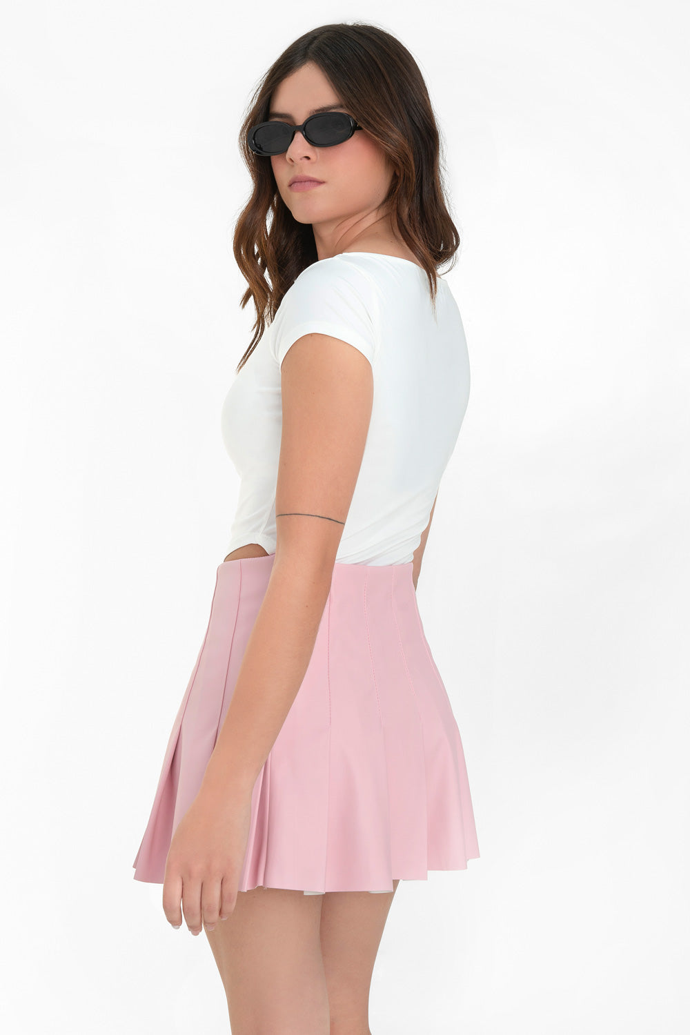 Falda corta de efecto piel, de corte en a, cintura alta con costuras y tableado en bajo. Cierre lateral con cremallera oculta.