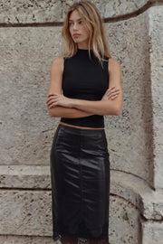 Falda midi de efecto piel, fit ajustado, cintura media, cortes decorativos, abertura lateral en bajo y encaje decorativo en borde. Cierre lateral con cremallera oculta.