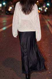 Falda midi satinada de corte en a, cintura alta, bajo asimétrico con encaje en borde y abertura frontal. Cierre lateral con cremallera oculta.