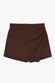 Falda short corto de cintura alta elástica y cruce frontal asimétrico con plisados laterales.