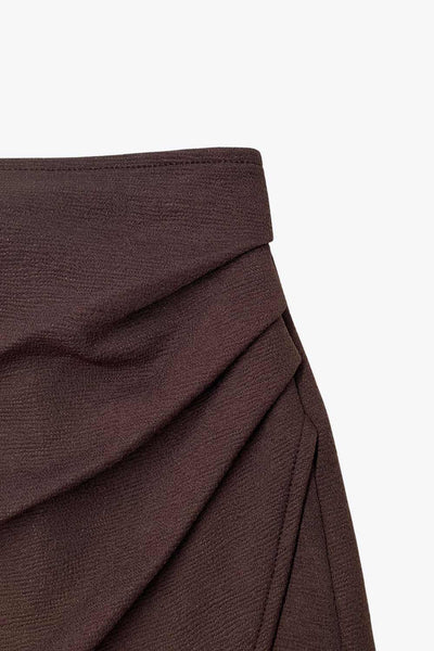 Falda short corto de cintura alta, corte en a, cruce frontal con plisados frontales y cierre lateral con cremallera oculta.