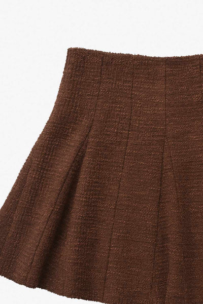 Falda short corto de bouclé, cintura alta, corte en a y olanes en bajo.