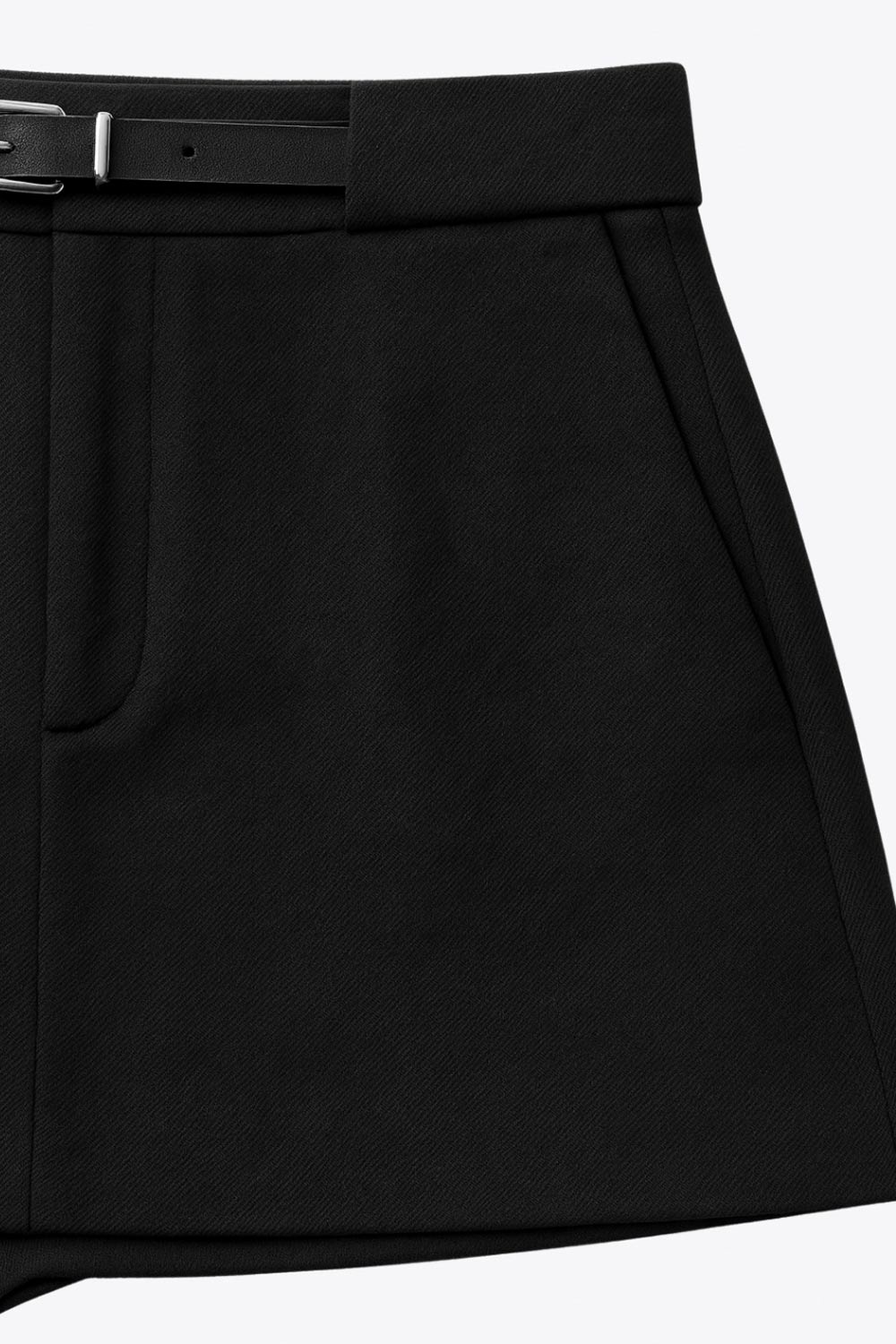 Falda short corto de fit recto, cintura alta con pretina y trabillas, vivos decorativos posteriores, cierre frontal con broche y cremallera ocultos. Detalle de cinturón en contraste con hebilla.