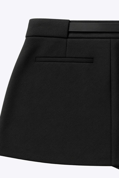 Falda short corto de fit recto, cintura alta con pretina y trabillas, vivos decorativos posteriores, cierre frontal con broche y cremallera ocultos. Detalle de cinturón en contraste con hebilla.