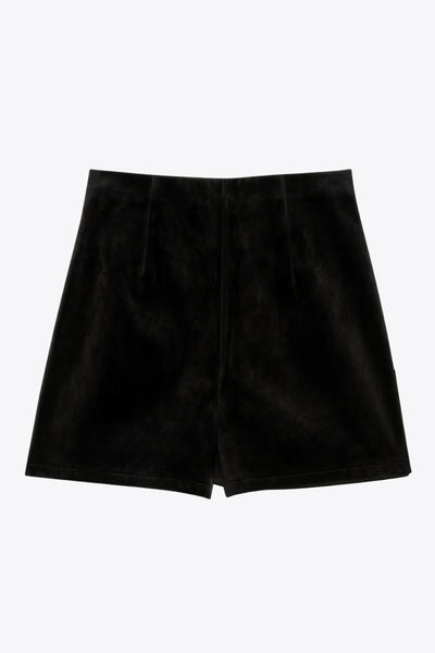 Falda short corto de efecto piel, fit ajustado, cintura alta elástica, cruce frontal asimétrico y plisados decorativos laterales.