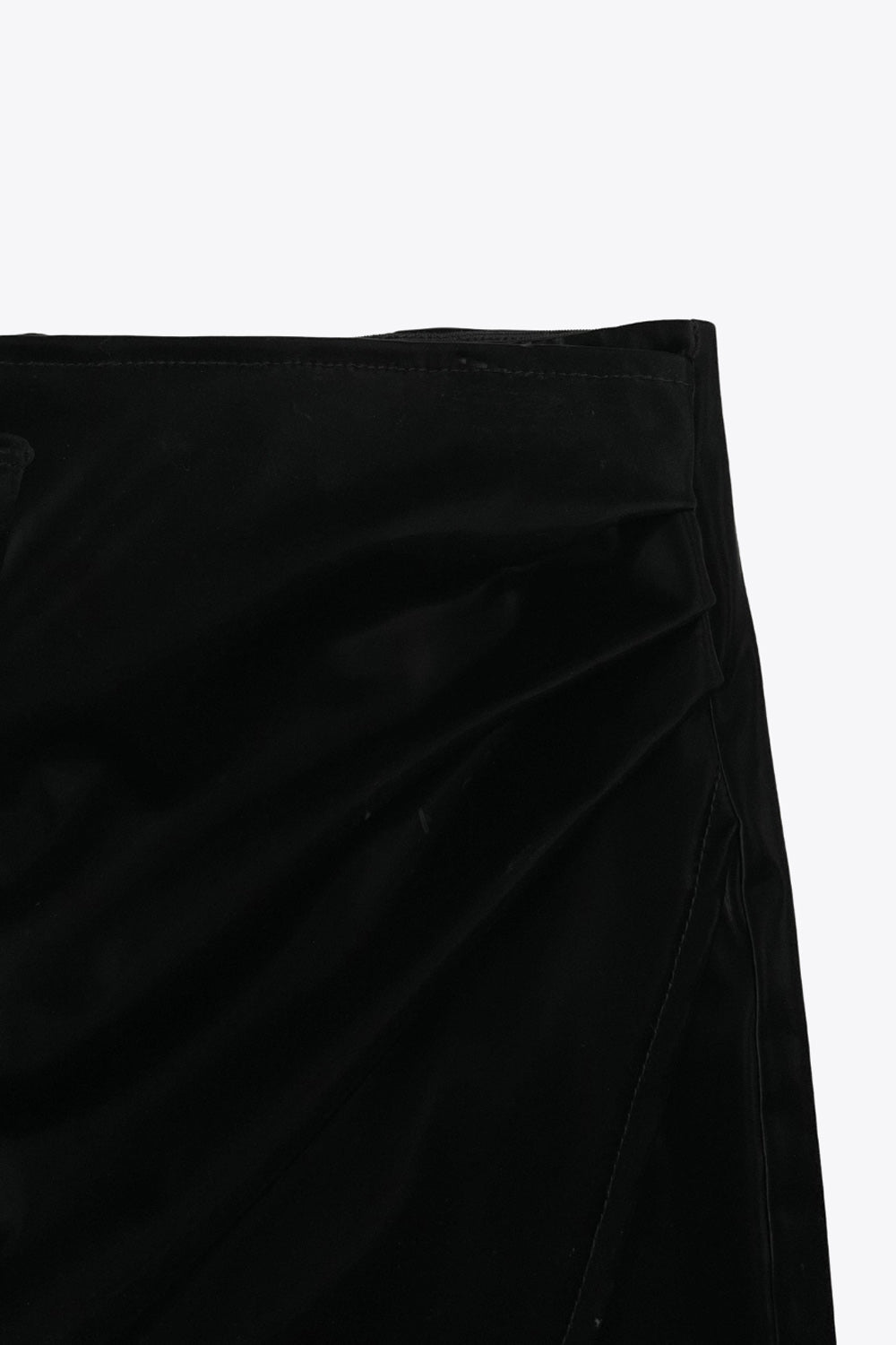 Falda short corto de efecto piel, fit ajustado, cintura alta elástica, cruce frontal asimétrico y plisados decorativos laterales.