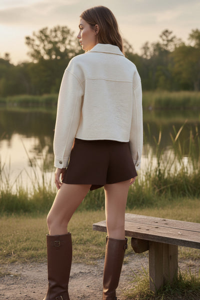 Falda short de fit ajustado, cintura alta, cruce frontal asimétrico, vivos decorativos posteriores y cierre lateral con cremallera oculta.