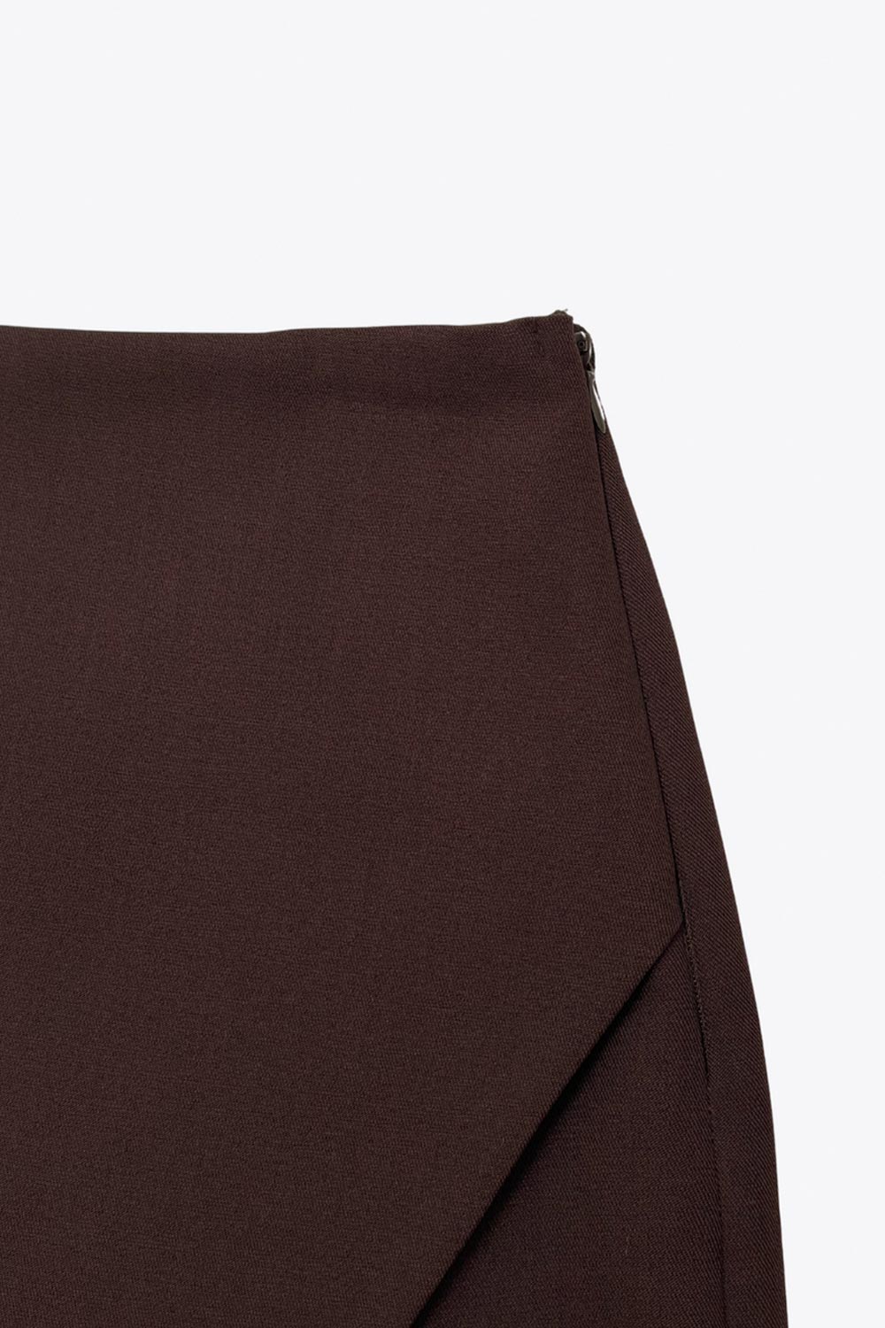 Falda short de fit ajustado, cintura alta, cruce frontal asimétrico, vivos decorativos posteriores y cierre lateral con cremallera oculta.