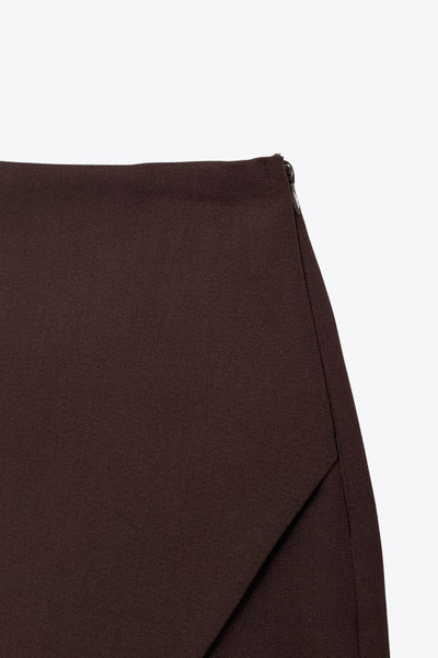 Falda short de fit ajustado, cintura alta, cruce frontal asimétrico, vivos decorativos posteriores y cierre lateral con cremallera oculta.